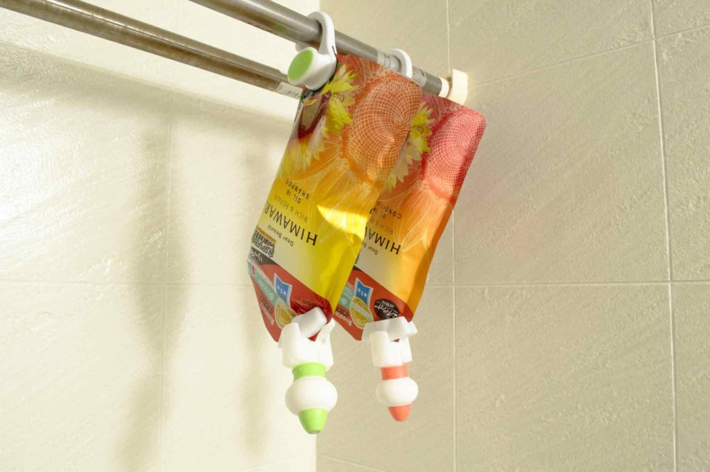 浴室乾燥機の洗濯物を吊るす棒にシャンプーとコンディショナーの詰め替え用パッケージを吊るす